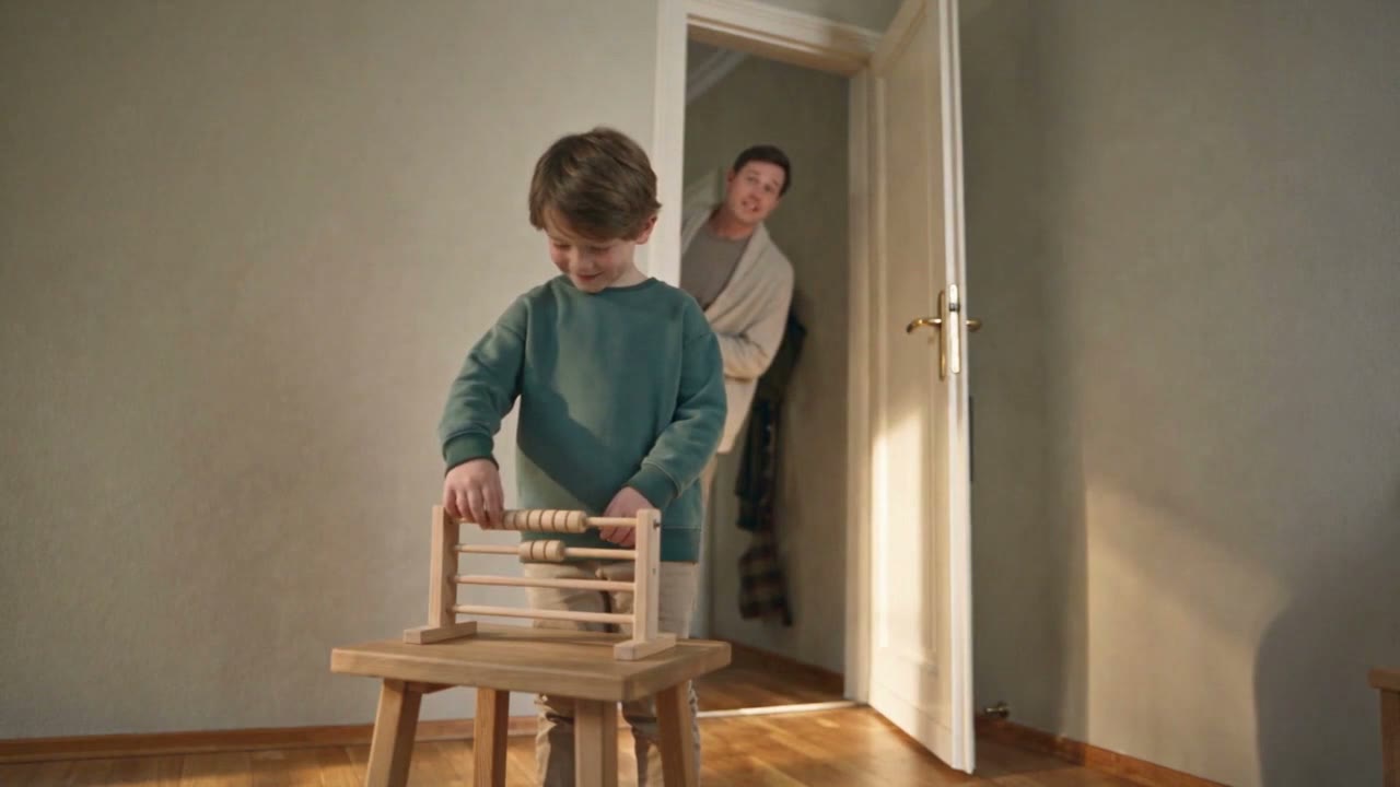 Ein Junge baut mit Holzklötzen, während sein Vater in die Tür schaut.